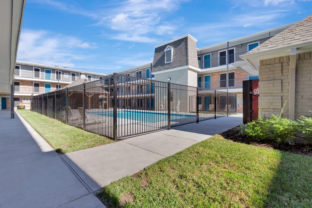 A black fence surrounds a pool in a residential area.
