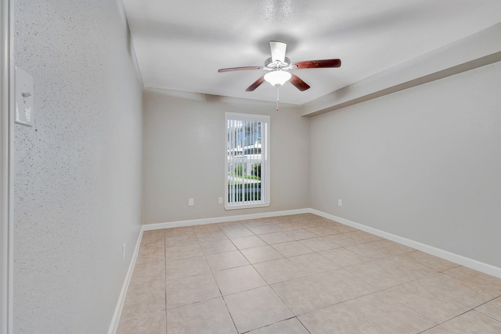 A room with a ceiling fan and tiled flooring.