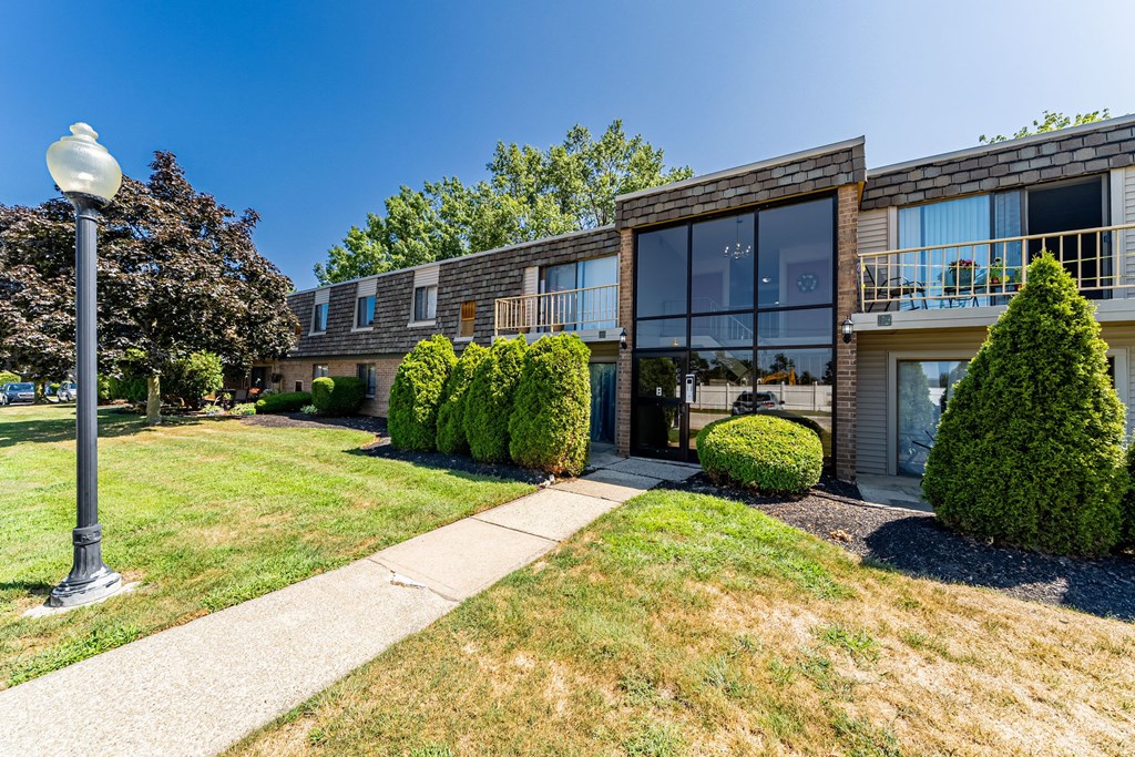 A modern building with a glass facade and a landscaped front yard.