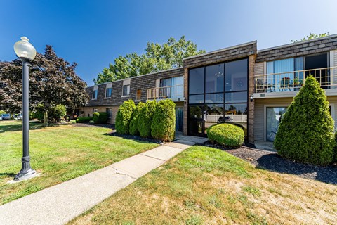 A modern building with a glass facade and a landscaped front yard.