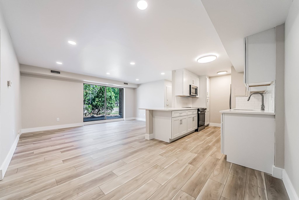 A spacious kitchen with wooden flooring and white cabinetry.