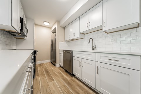 A kitchen with white cabinets and a wooden floor.