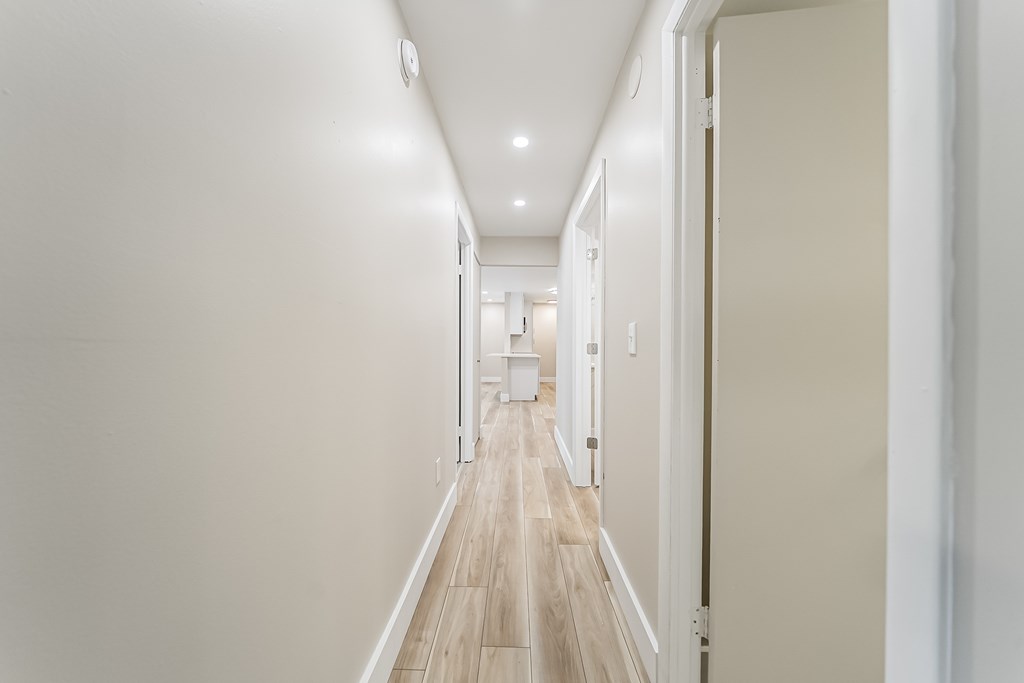 A long hallway with white walls and wood floors.