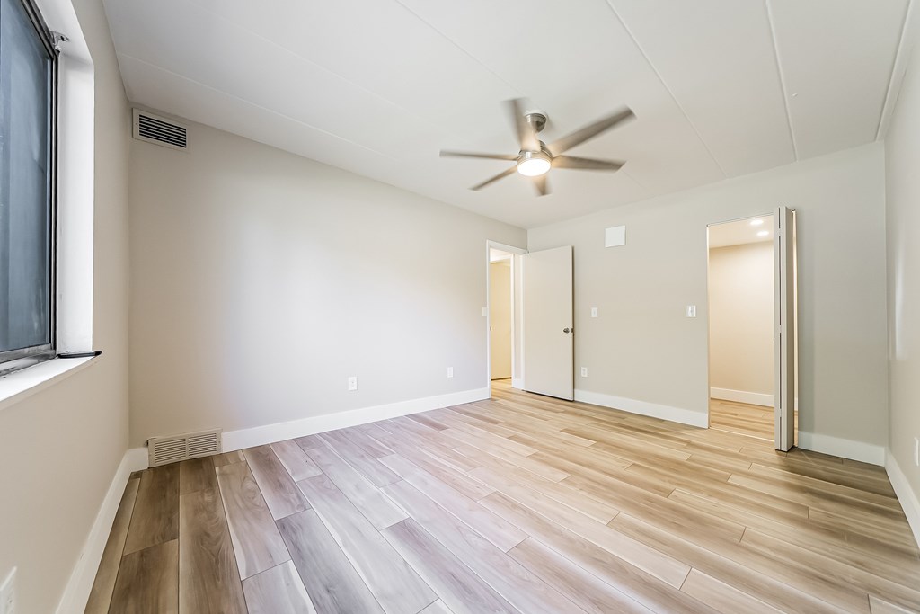 A room with a ceiling fan and wooden flooring.