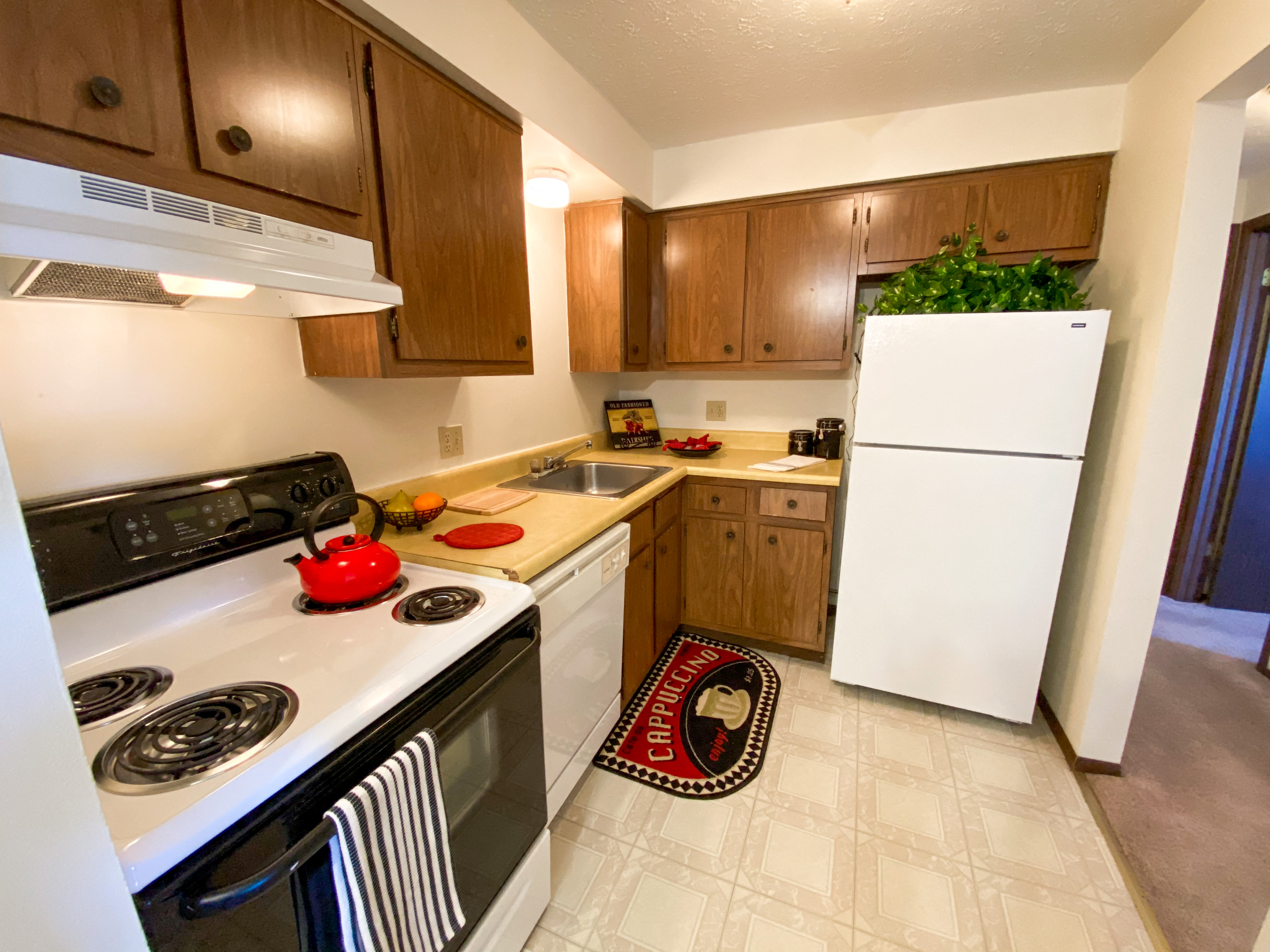 A kitchen with a white stove top oven and a white refrigerator.