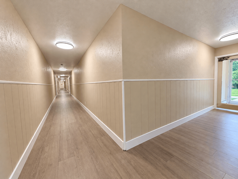 A long hallway with wooden floors and white walls.