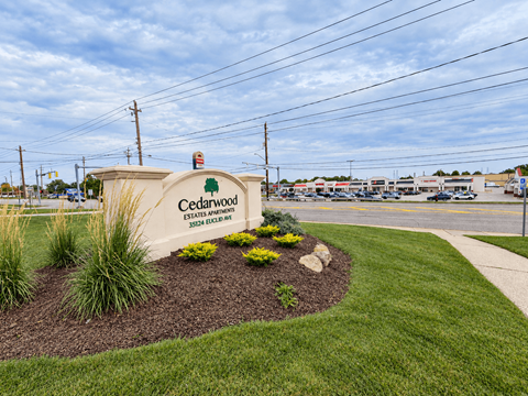 A sign for Cedarwood Estates is surrounded by a flower bed.