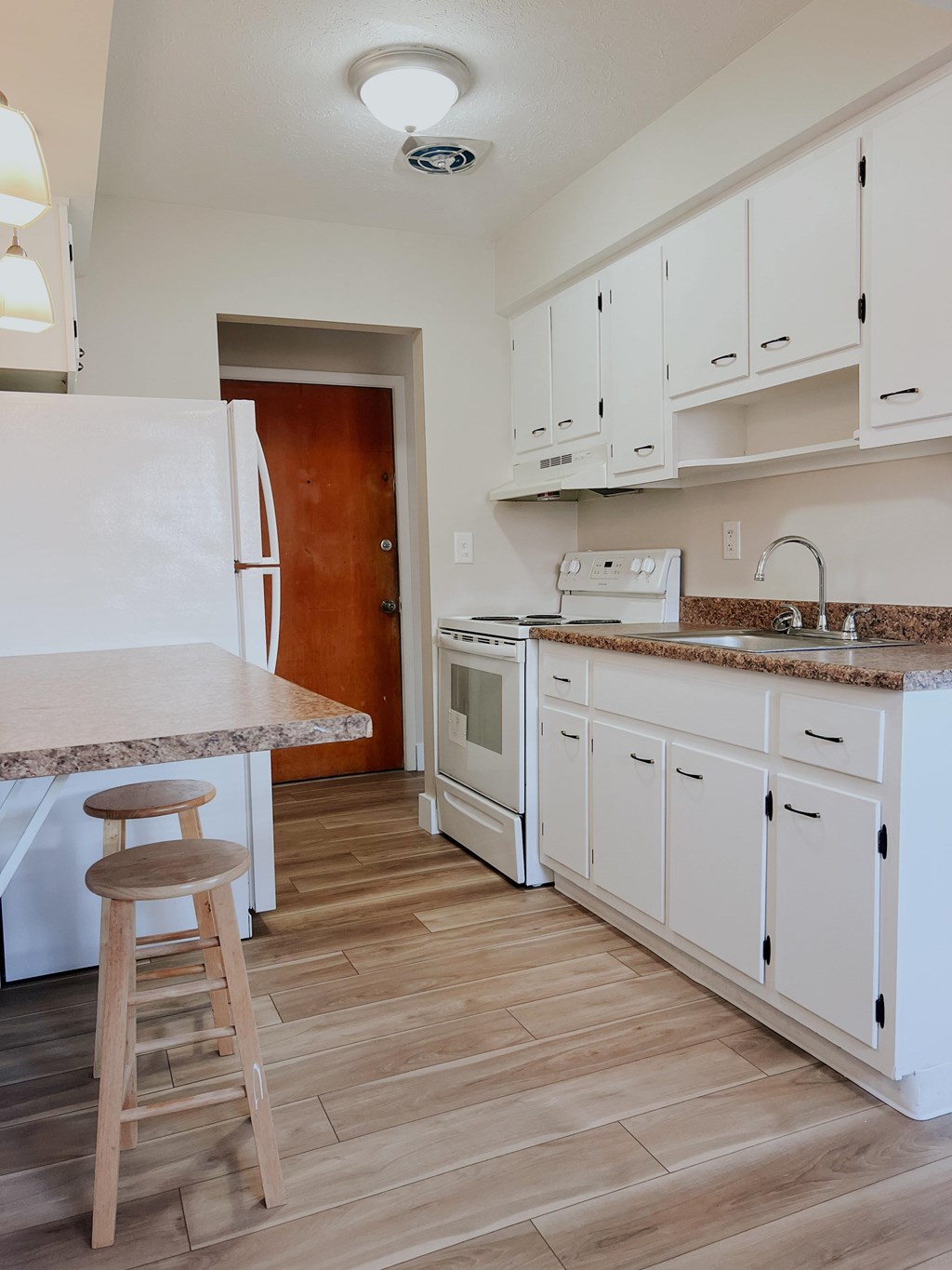 A kitchen with white cabinets and a wooden floor.