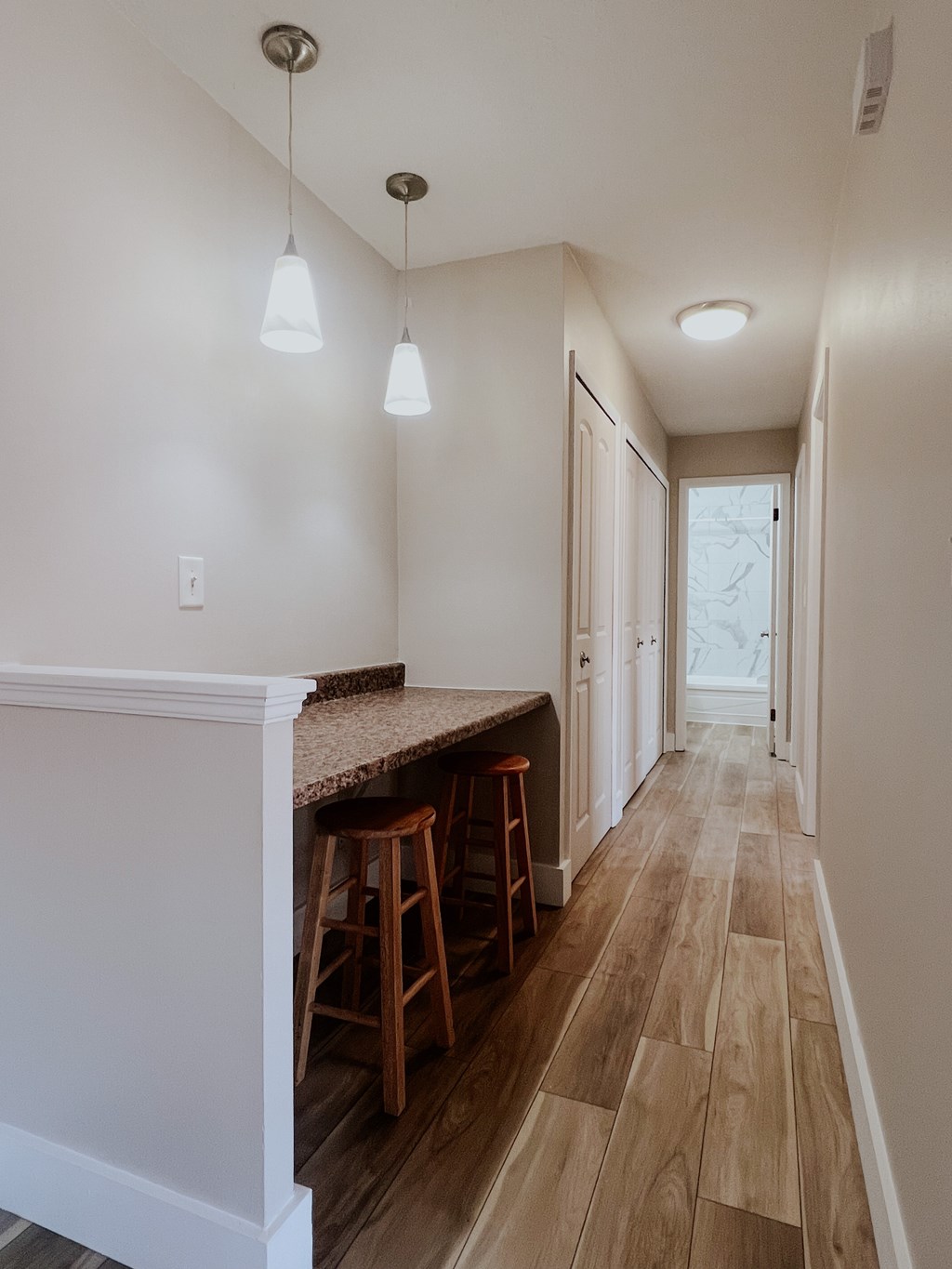 A long hallway with a bar and stools on the left.