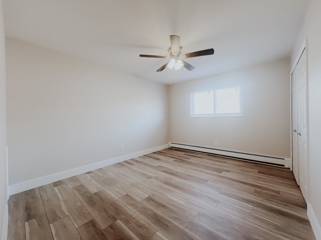 A room with a ceiling fan and wooden flooring.