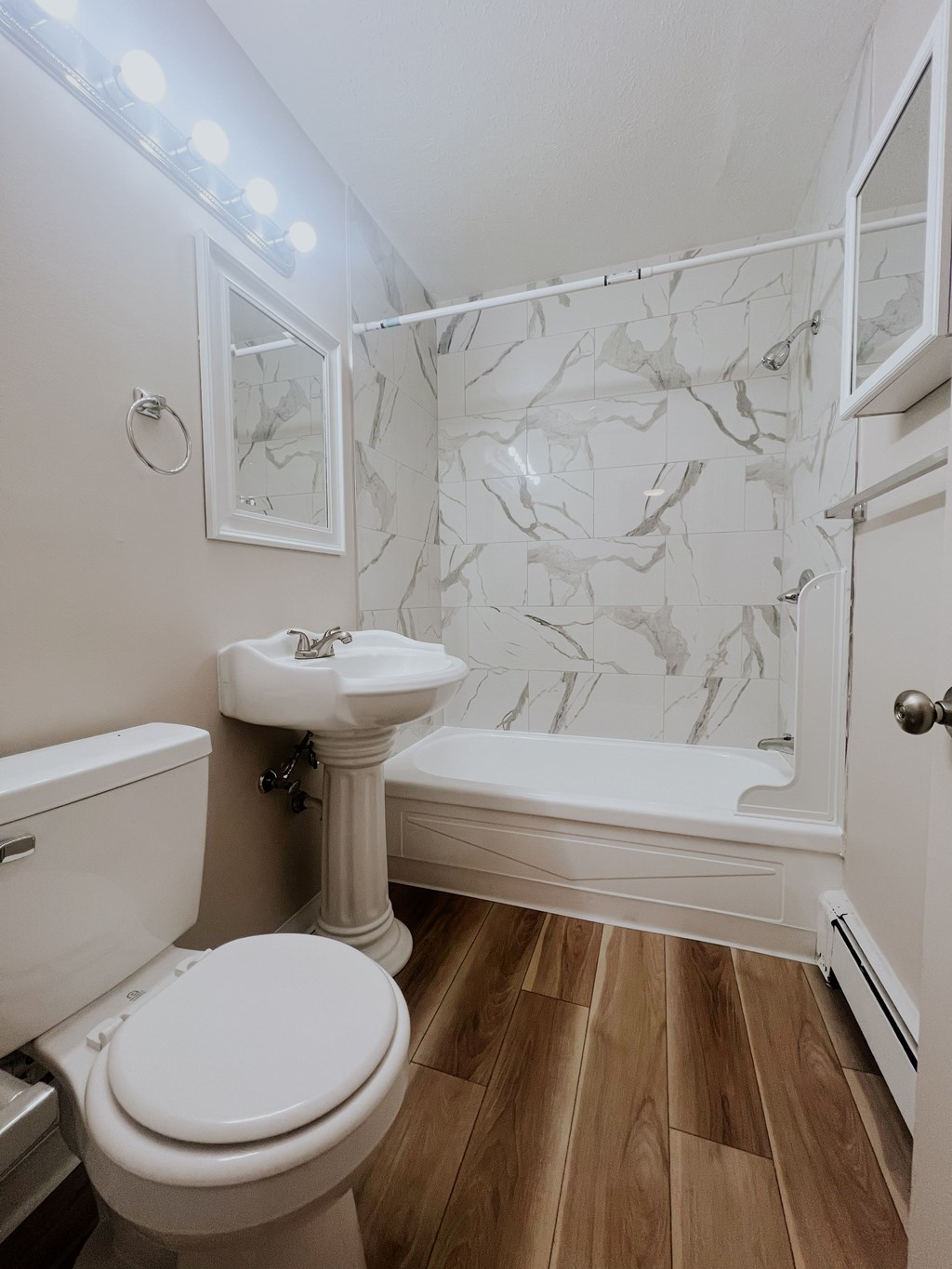 A white toilet sits next to a white sink in a bathroom with a marble wall.