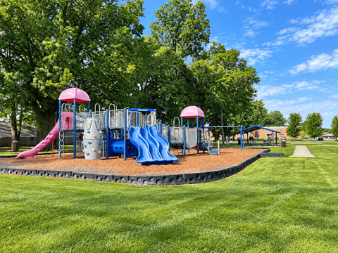 A playground with a blue slide and a pink slide.