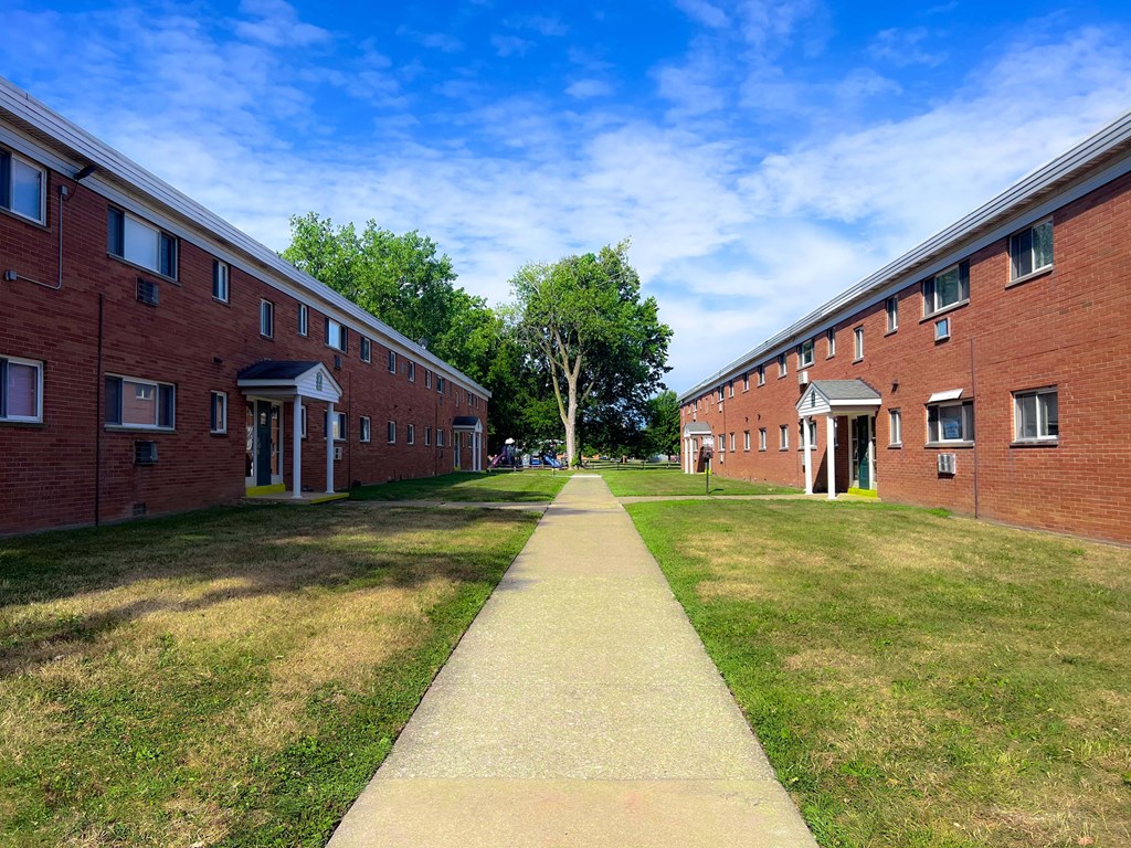 A long pathway leads between two rows of red brick buildings.