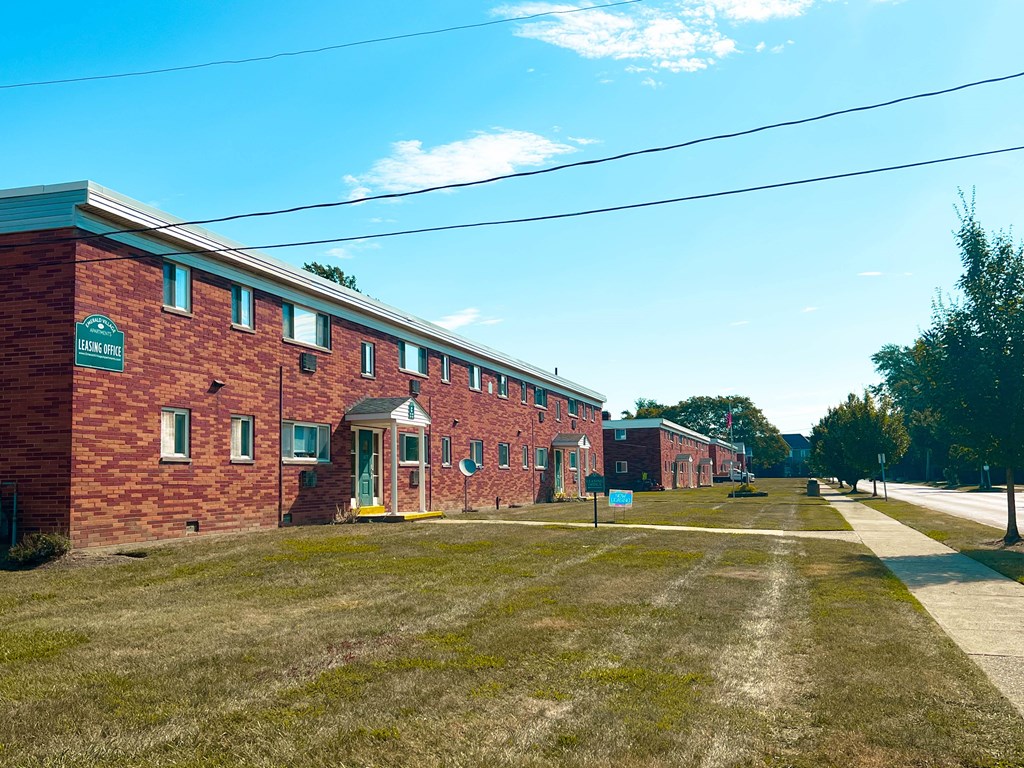 A long brick building with a green sign on the front.
