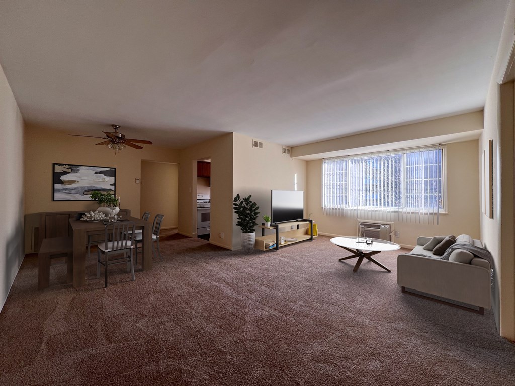 a living room with a big window, couch, table, and tv on tv stand and a dining room with table and chairs and a ceiling fan