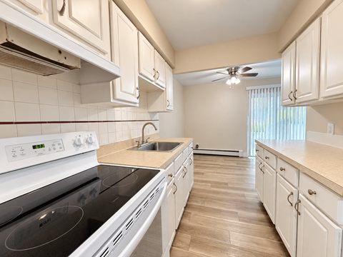 A kitchen with white cabinets and a black stove top.