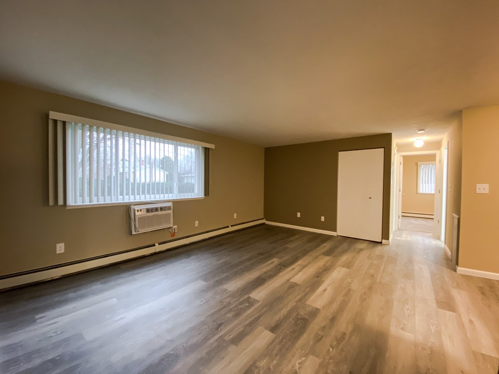 an empty living room with plank floors and a window