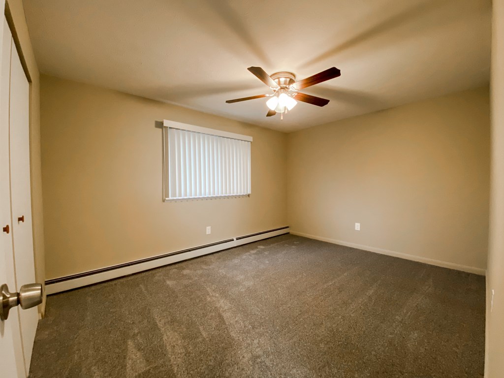 the spacious bedroom with carpet and a ceiling fan