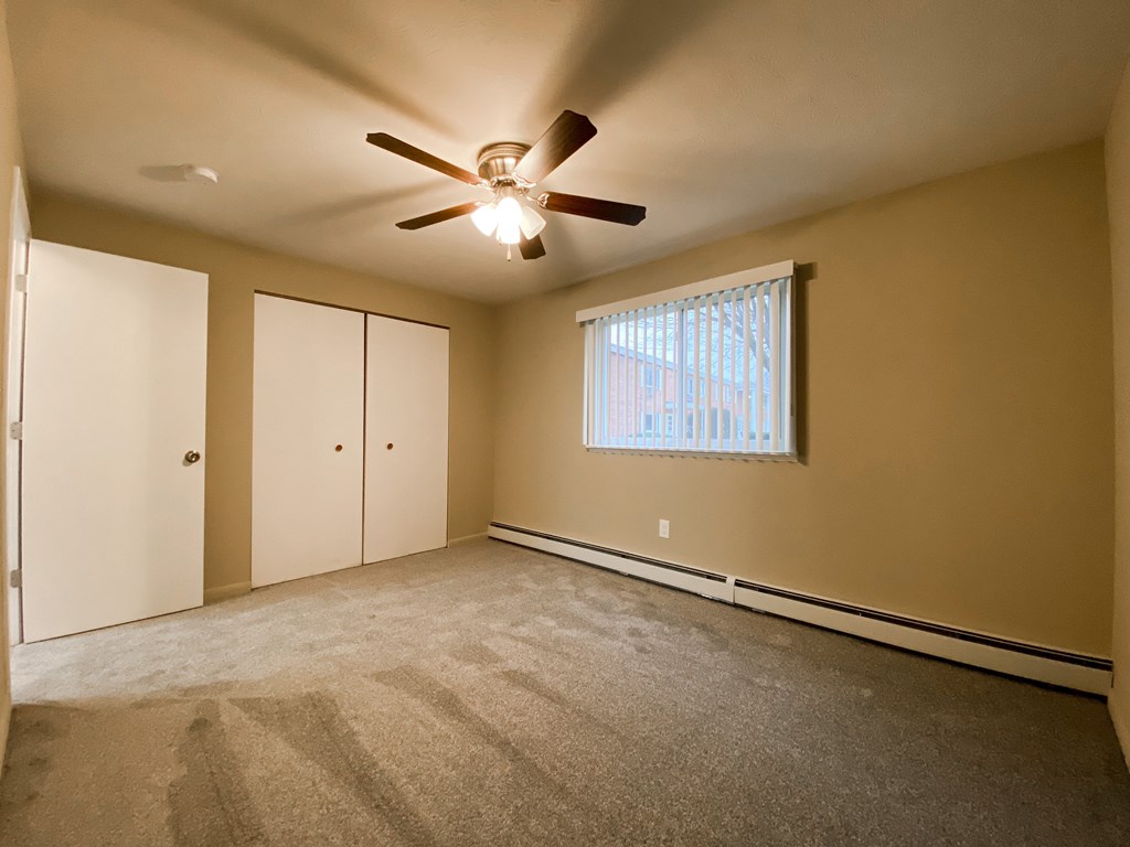 an empty bedroom with a ceiling fan and a window