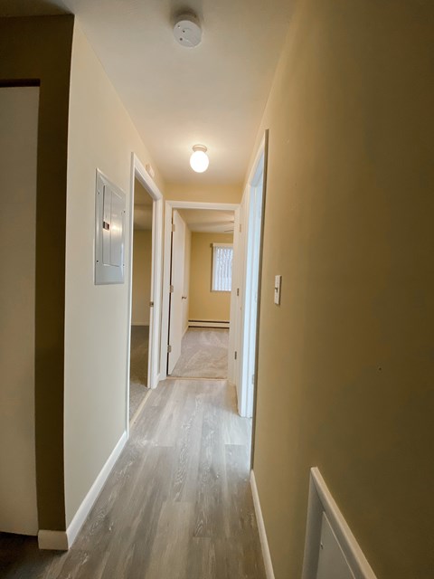 a view of a hallway with plank floors and a door to a bedroom