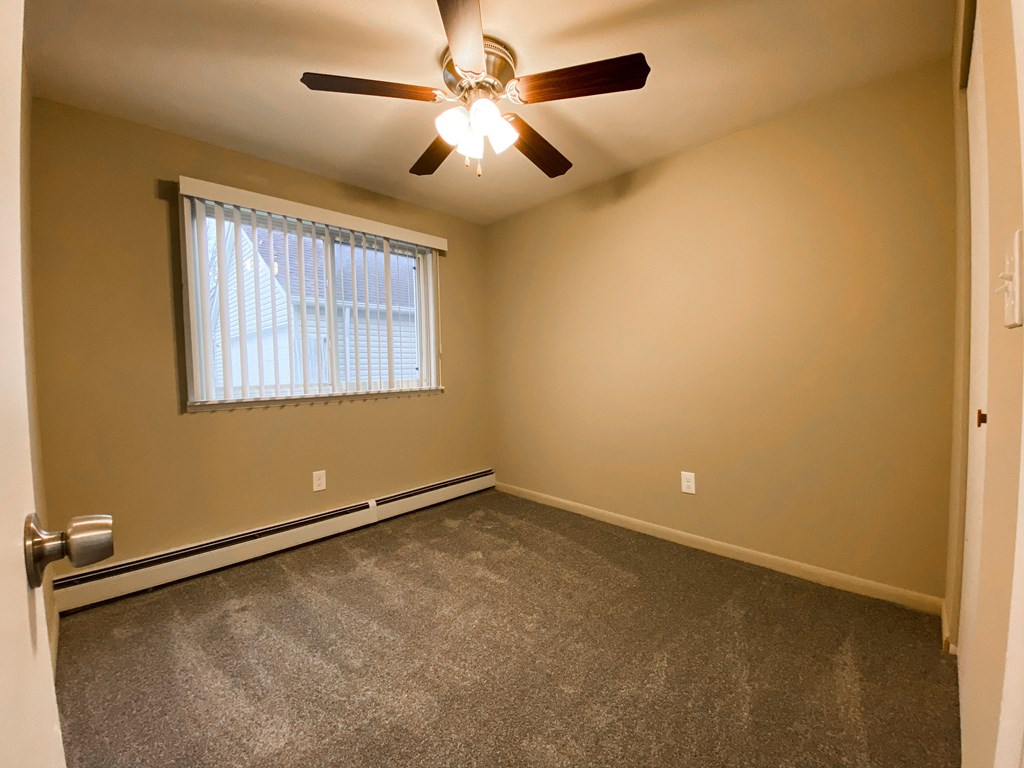 an empty bedroom with a ceiling fan and a window