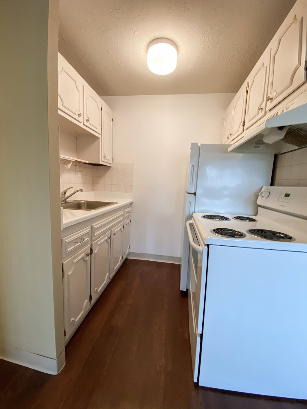 an empty kitchen with white appliances and white cabinets