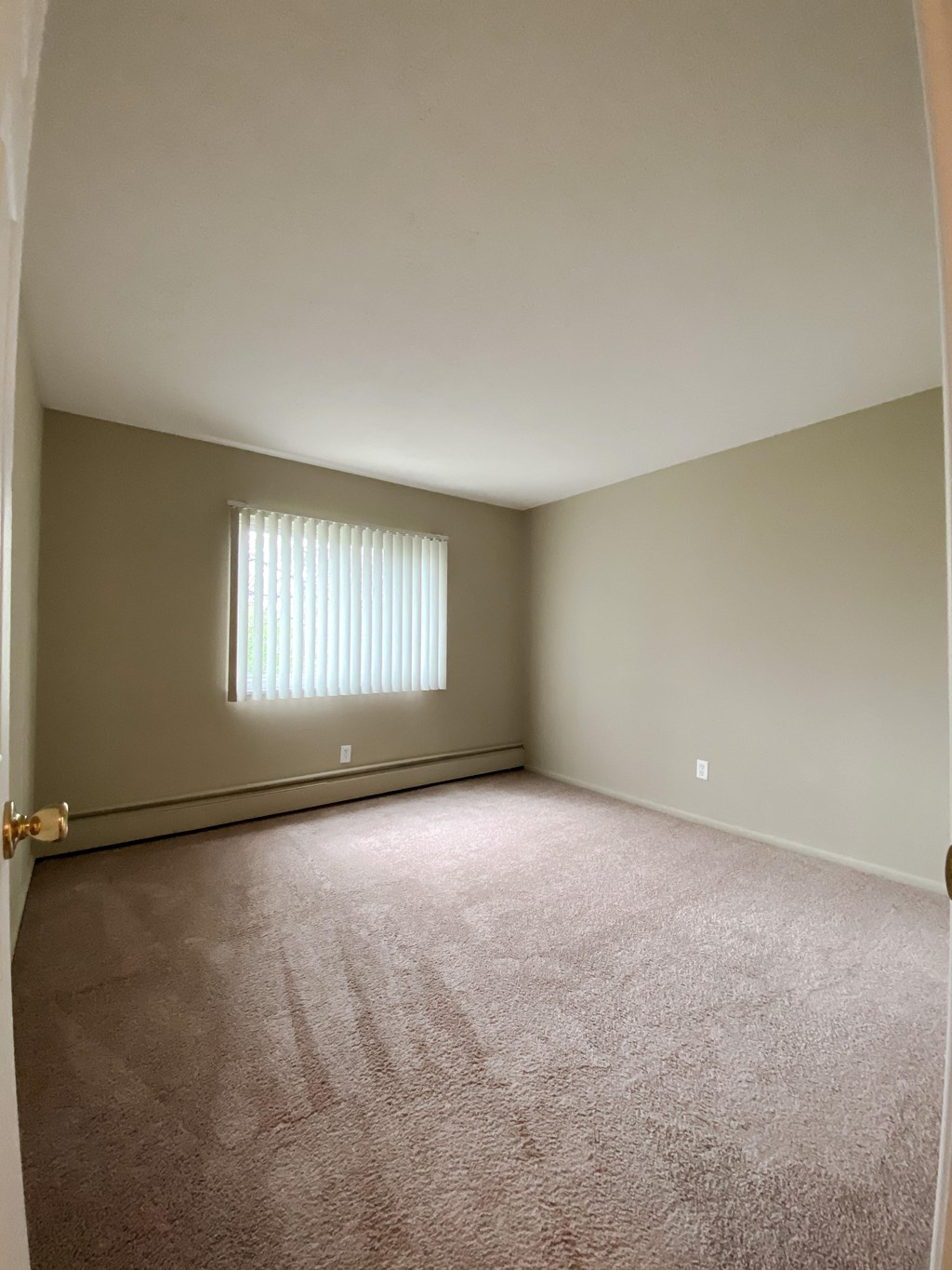 an empty bedroom with carpet and a window