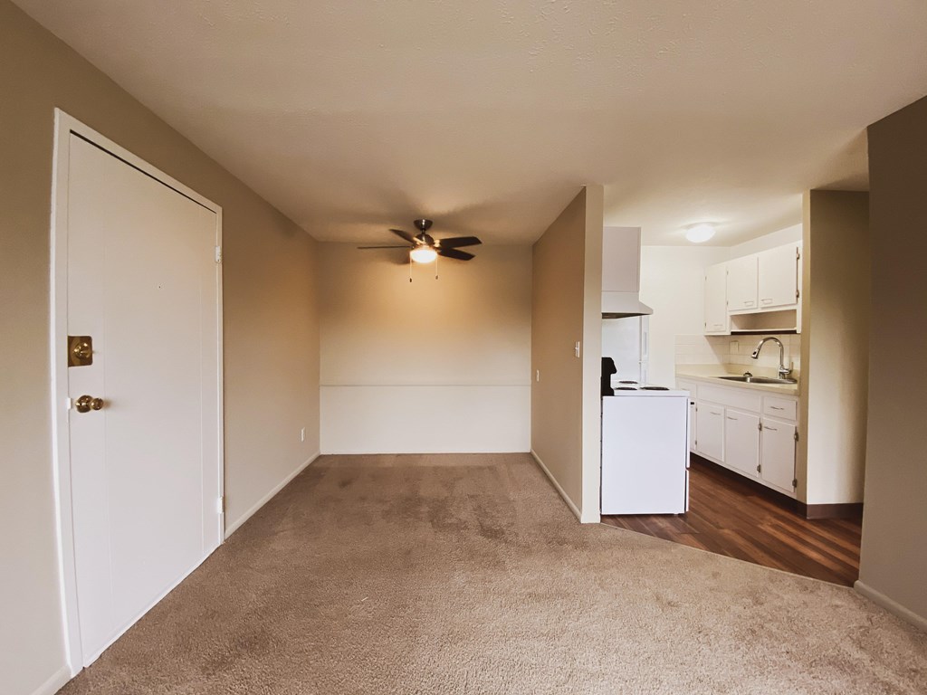 an empty dining area with a ceiling fan and kitchen