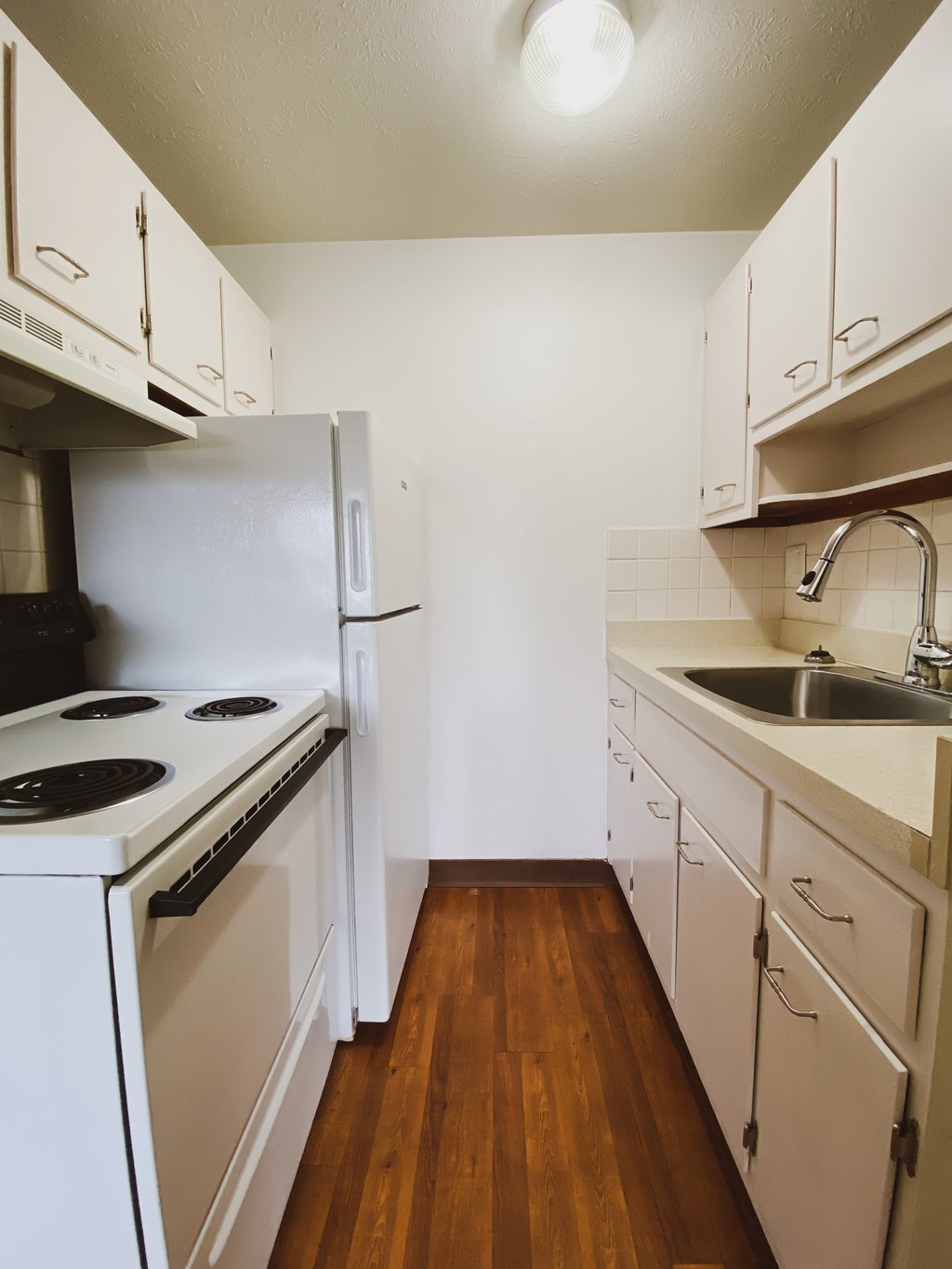 an empty kitchen with white cabinets and appliances and a sink