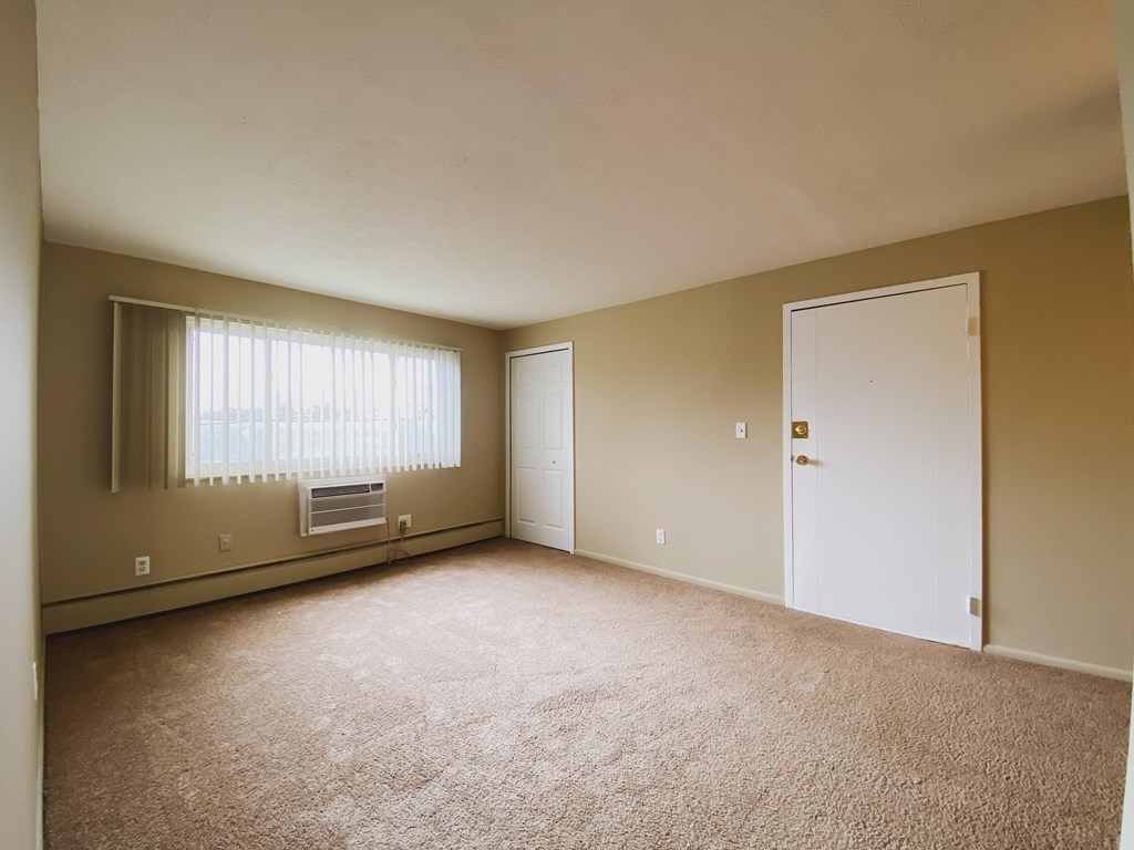 an empty living room with a white door and a window