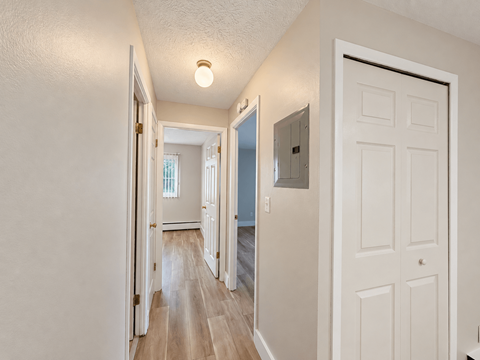 A hallway with a white door on the right and a light on the ceiling.