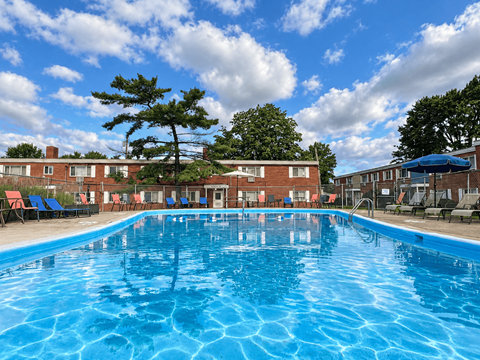 A large blue swimming pool in front of a building with red brick walls.