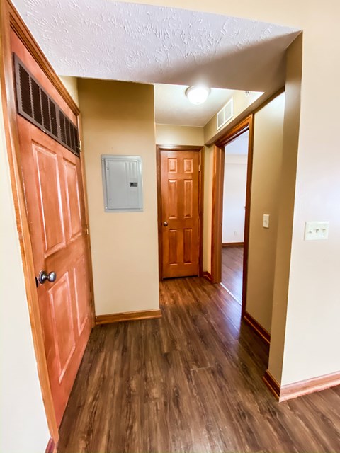 an empty hallway with a wooden door and a door to a bedroom and a hallway at Hallwood Manor Apartments, Mentor, OH
