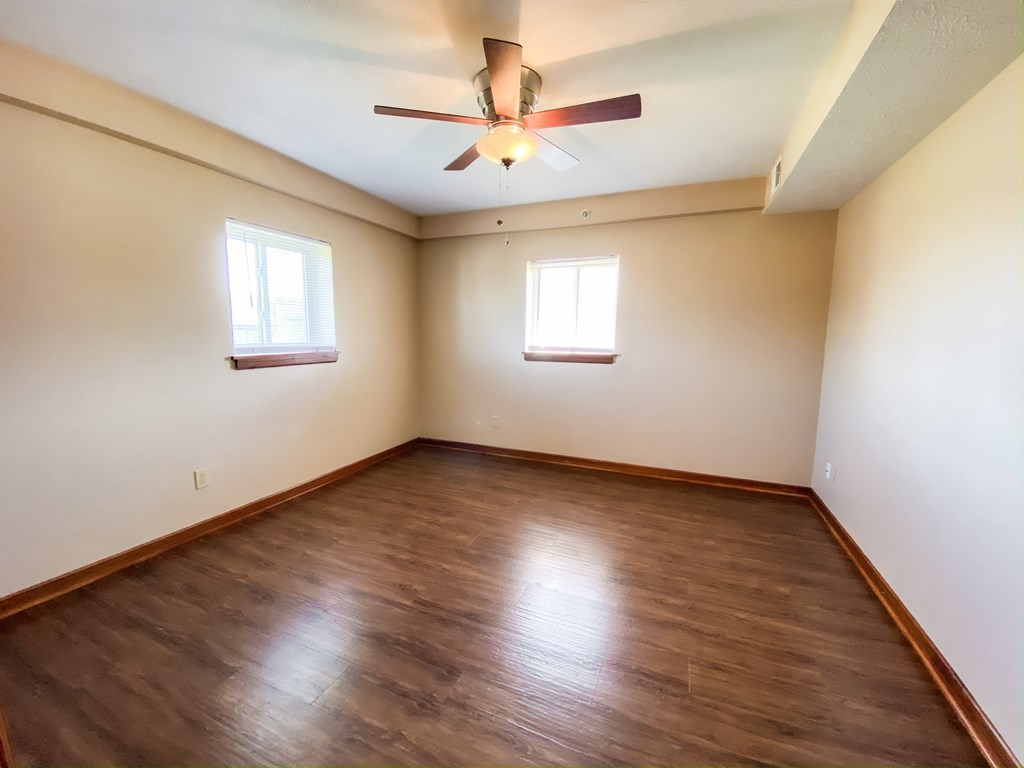 an empty bedroom with wooden floors and a ceiling fan at Hallwood Manor Apartments, Mentor