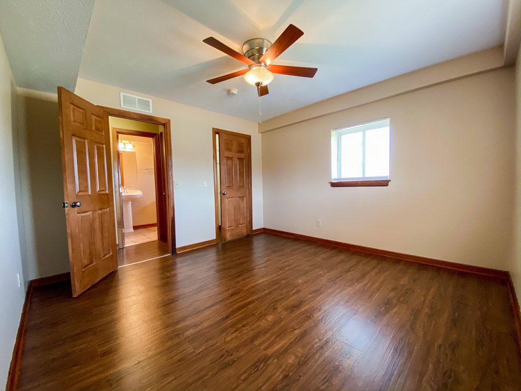 an empty bedroom with wooden floors and a ceiling fan at Hallwood Manor Apartments, Mentor