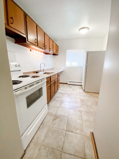 an empty kitchen with white appliances and wooden cabinets