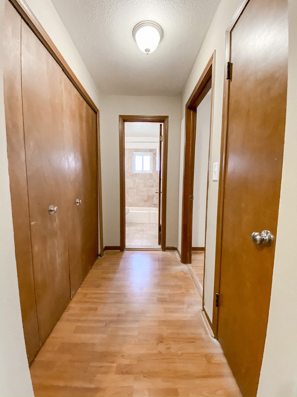 a long hallway with wooden doors and a door to a bathroom at Hallwood Manor Apartments, Mentor, OH, 44060