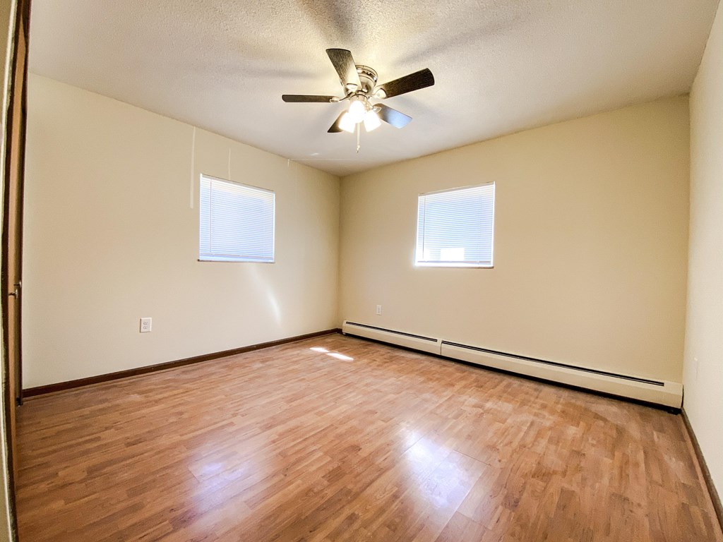 an empty bedroom with wood floors and a ceiling fan at Hallwood Manor Apartments, Mentor, Ohio