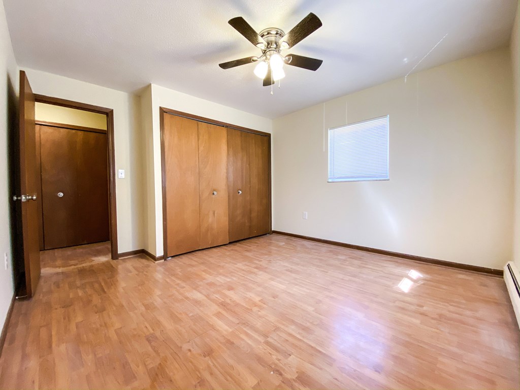 an empty bedroom with wooden floors and a ceiling fan at Hallwood Manor Apartments, Mentor, OH, 44060