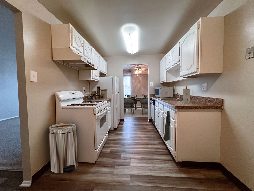 a kitchen with white appliances and white cabinets and a vinyl floor