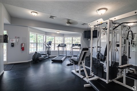 A well-equipped gym with a variety of machines and a fire extinguisher on the wall.