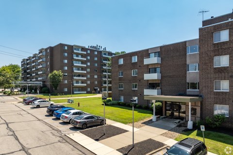 A parking lot with cars and two apartment buildings.