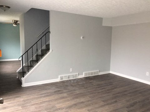 an empty living room with wood floors and a staircase