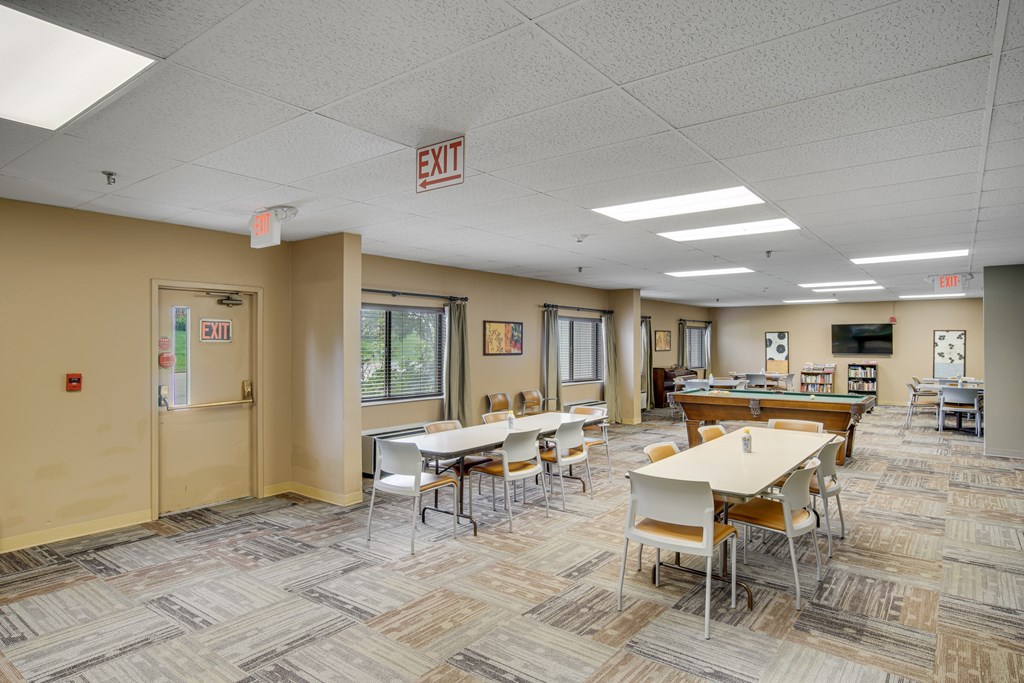 A room with tables and chairs and an exit sign on the ceiling at Independence Place Apartments, Parma Heights, 44130