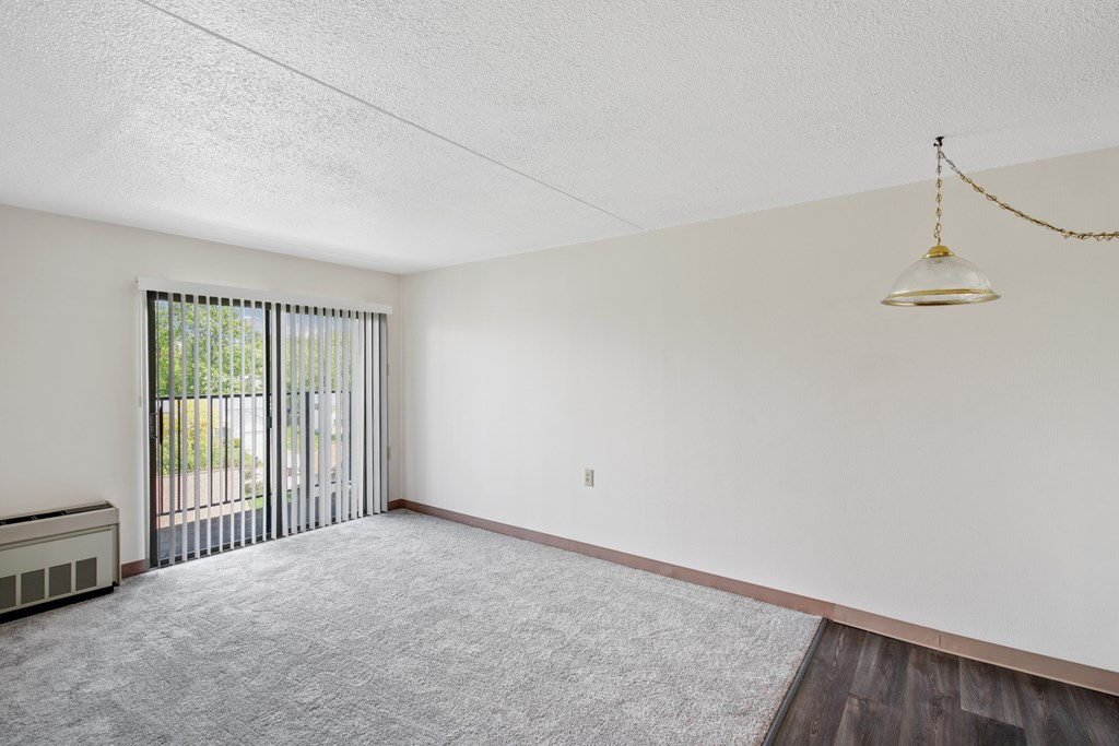 A room with a grey carpet and a white wall with a hanging light fixture at Independence Place Apartments, Ohio