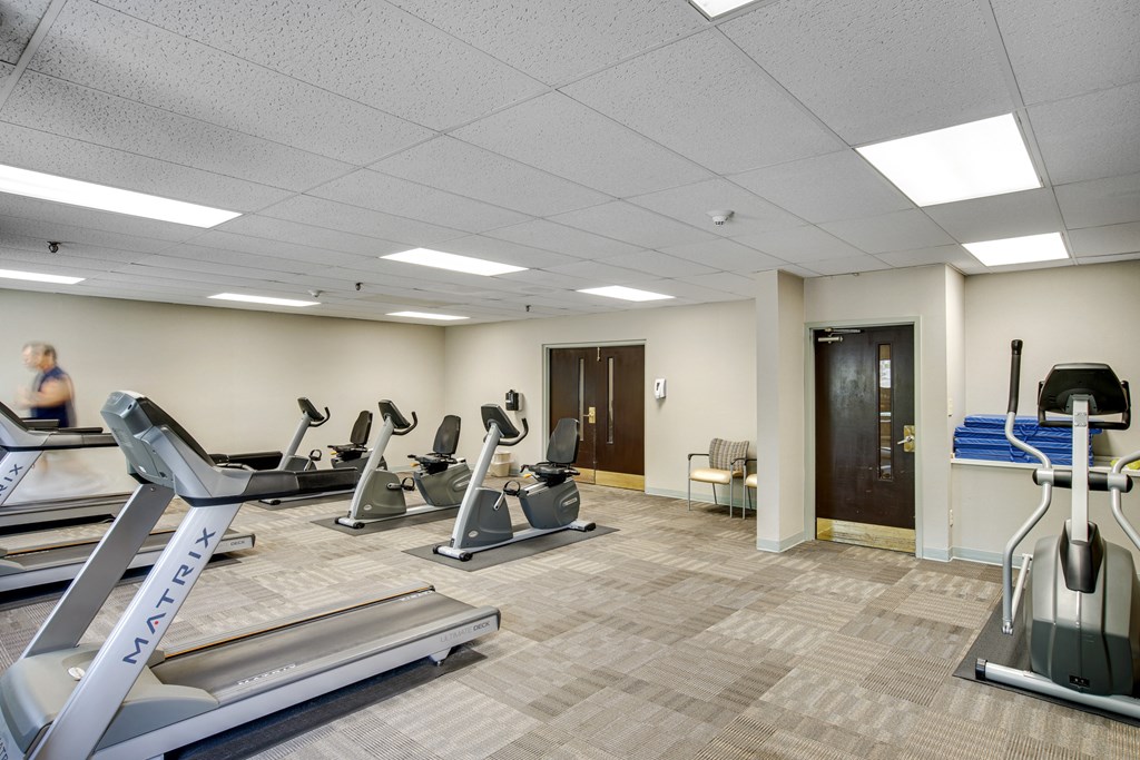 A gym with treadmills, elliptical machines, and a woman walking at Independence Place Apartments, Ohio 44130