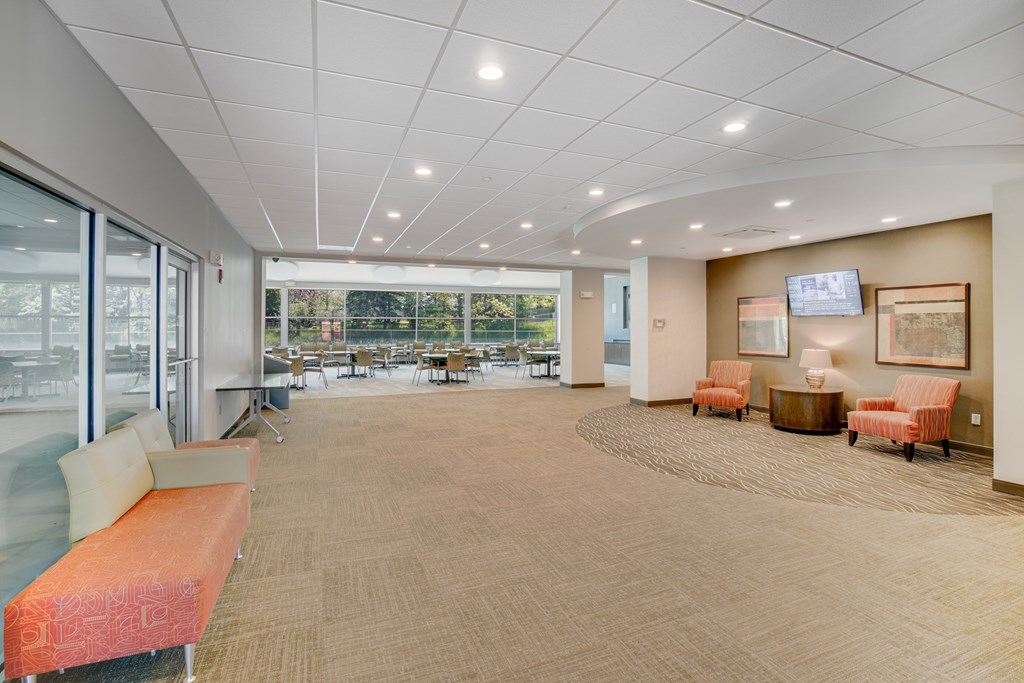 A spacious waiting area with orange and beige furniture at Independence Place Apartments, Parma Heights
