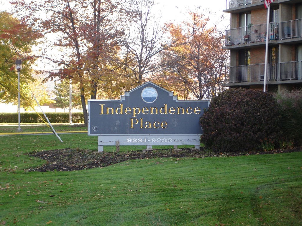 A sign for Independence Place stands in a grassy area at Independence Place Apartments, Parma Heights