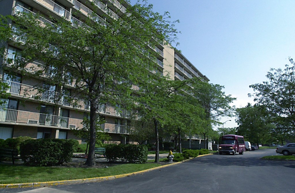 A street view of a residential area with apartment buildings and parked cars at Independence Place Apartments, Parma Heights, Ohio