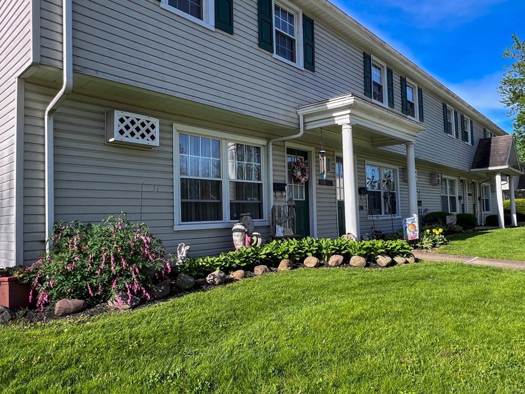 the front of a townhouse with landscaping on the yard